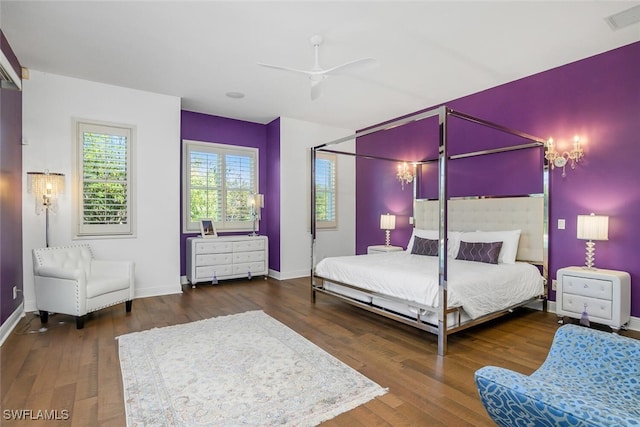bedroom featuring visible vents, ceiling fan, baseboards, and wood finished floors