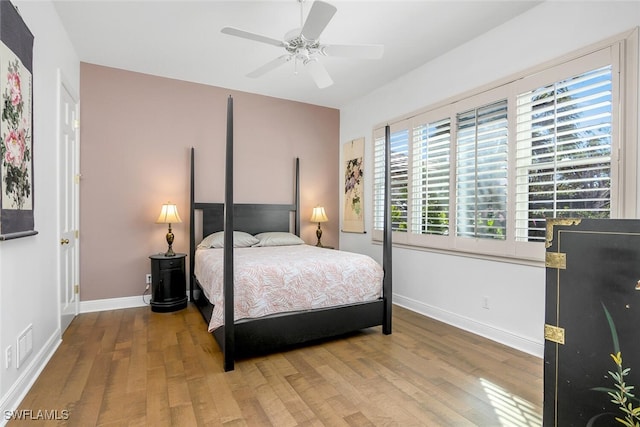 bedroom with ceiling fan, wood finished floors, and baseboards