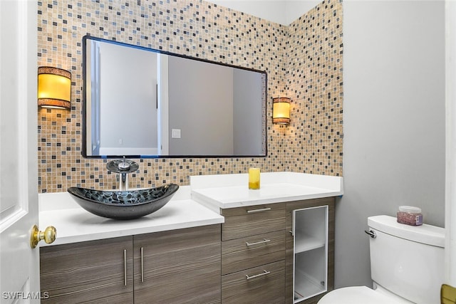 bathroom featuring toilet, vanity, and decorative backsplash