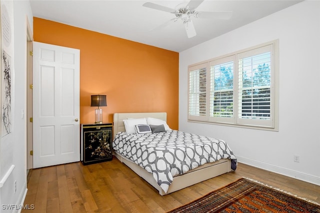 bedroom with a ceiling fan, baseboards, and wood finished floors