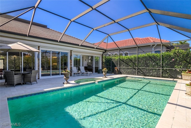 view of pool with a lanai, a pool with connected hot tub, and a patio