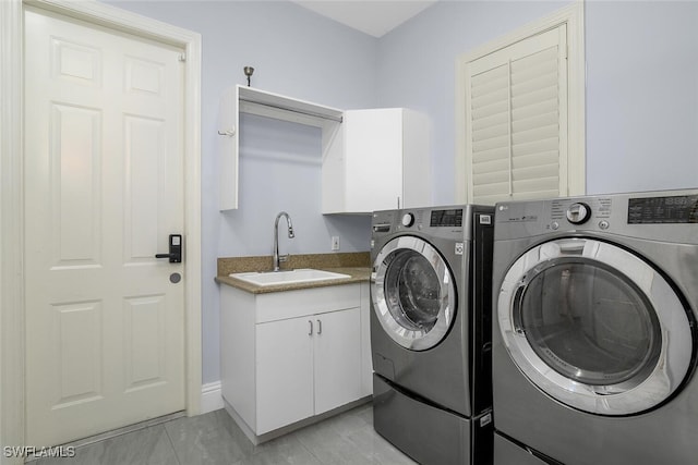 clothes washing area with washer and dryer, cabinet space, and a sink