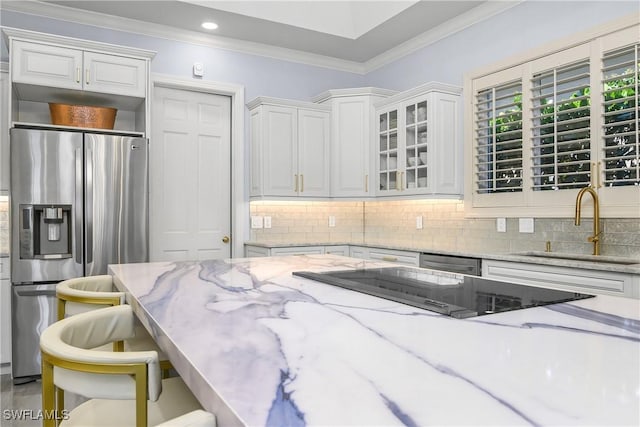 kitchen featuring stainless steel appliances, a sink, a kitchen breakfast bar, ornamental molding, and decorative backsplash