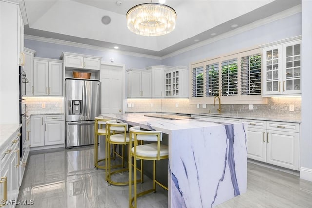 kitchen with ornamental molding, a tray ceiling, a center island, and stainless steel fridge