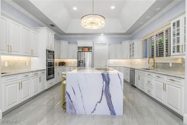 kitchen with a notable chandelier, a sink, white cabinets, appliances with stainless steel finishes, and a raised ceiling