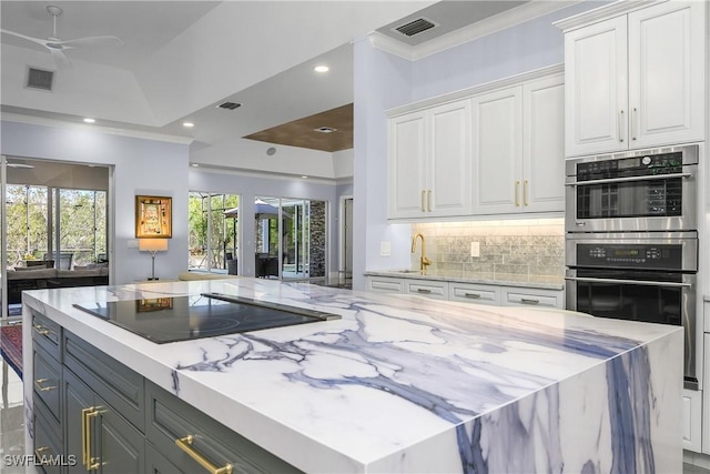 kitchen featuring visible vents, black electric cooktop, double oven, white cabinetry, and backsplash