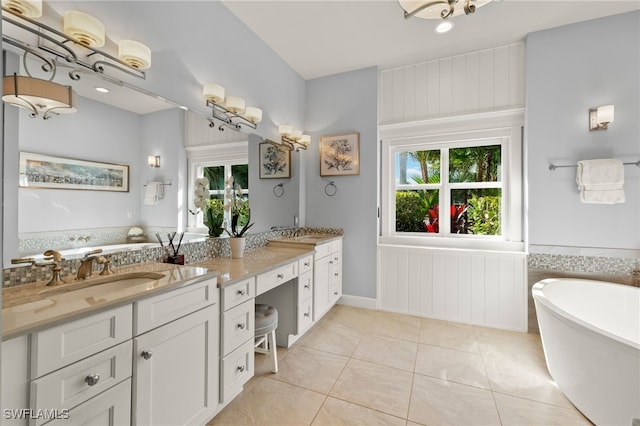 full bath featuring double vanity, a freestanding tub, tile patterned flooring, and a sink