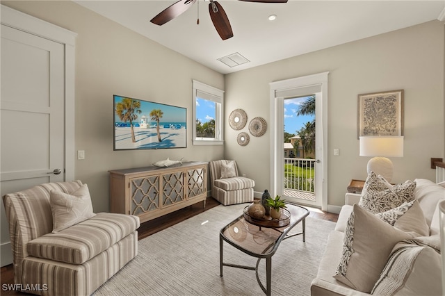 living room with ceiling fan, visible vents, light wood-style flooring, and baseboards