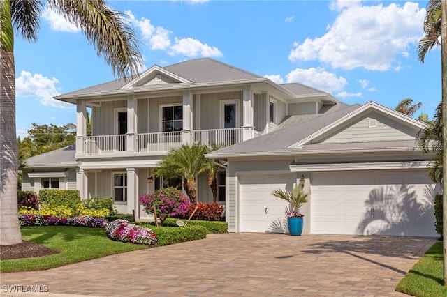 view of front of house featuring board and batten siding, decorative driveway, a balcony, and an attached garage