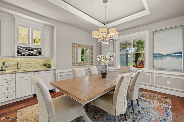 dining room featuring dark wood-style floors, a tray ceiling, a wainscoted wall, a decorative wall, and an inviting chandelier