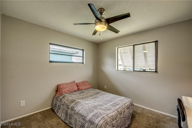 bedroom with a textured ceiling, dark colored carpet, and baseboards