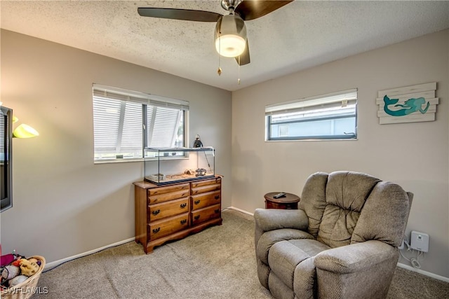 living area featuring light carpet, ceiling fan, a textured ceiling, and baseboards