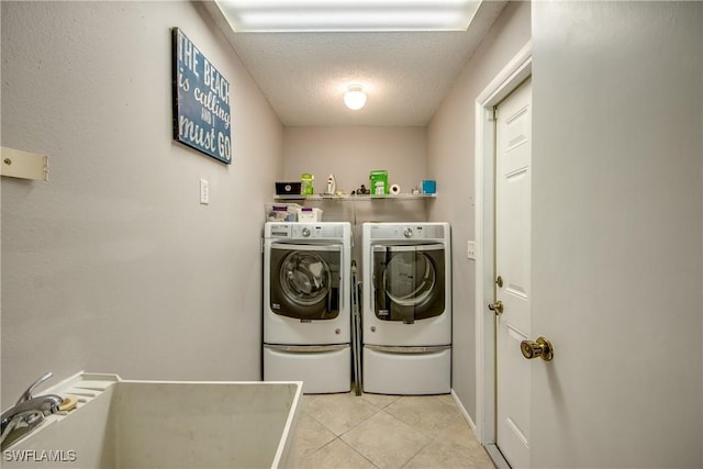 clothes washing area featuring laundry area, washing machine and clothes dryer, a textured ceiling, a sink, and light tile patterned flooring