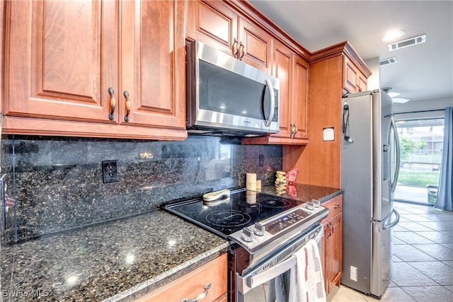 kitchen with stainless steel appliances, brown cabinetry, visible vents, and backsplash