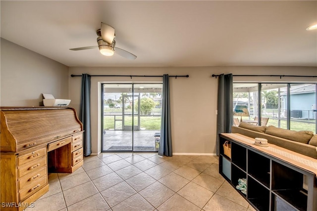 interior space with a healthy amount of sunlight, light tile patterned floors, ceiling fan, and baseboards