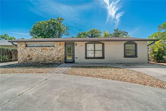 ranch-style house featuring stone siding and stucco siding