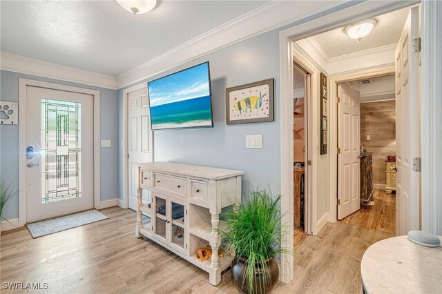 foyer entrance with light wood-style flooring, crown molding, and baseboards