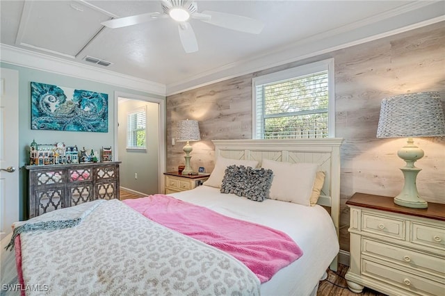 bedroom with a ceiling fan, ornamental molding, multiple windows, and visible vents
