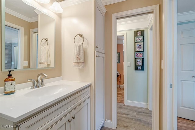 bathroom with baseboards, ornamental molding, wood finished floors, and vanity