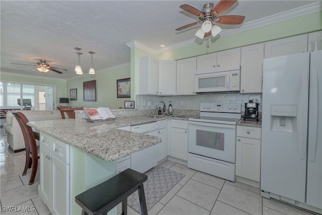 kitchen with kitchen peninsula, ornamental molding, white appliances, white cabinets, and a breakfast bar area