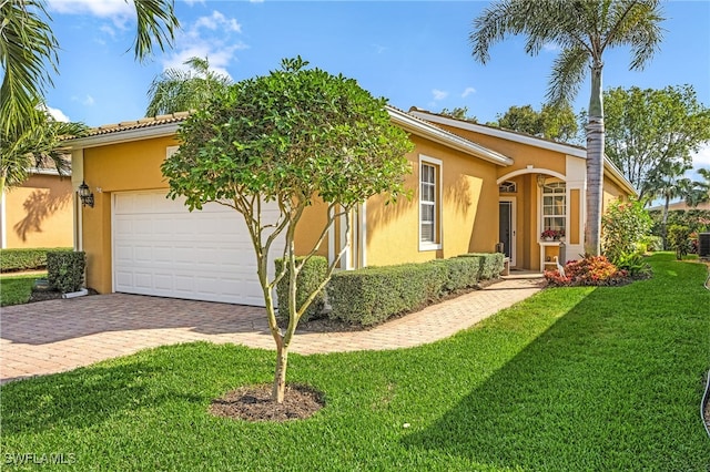 view of front of home featuring a garage, decorative driveway, a front lawn, and stucco siding