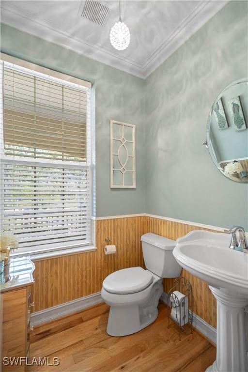 bathroom with ornamental molding, hardwood / wood-style flooring, wooden walls, and toilet