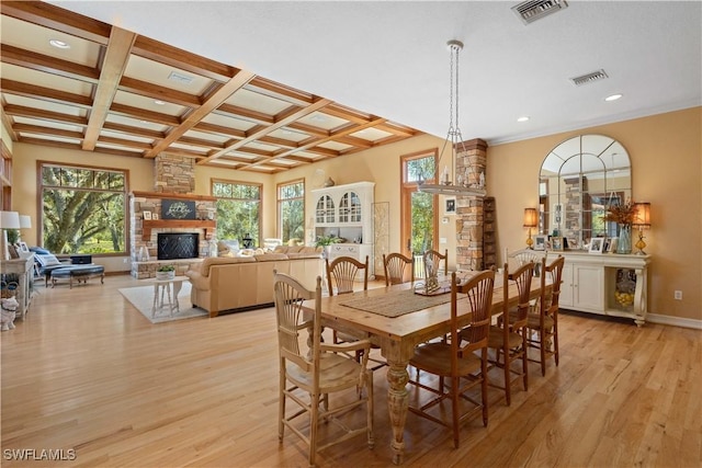 dining room featuring coffered ceiling, beam ceiling, light hardwood / wood-style floors, and a fireplace