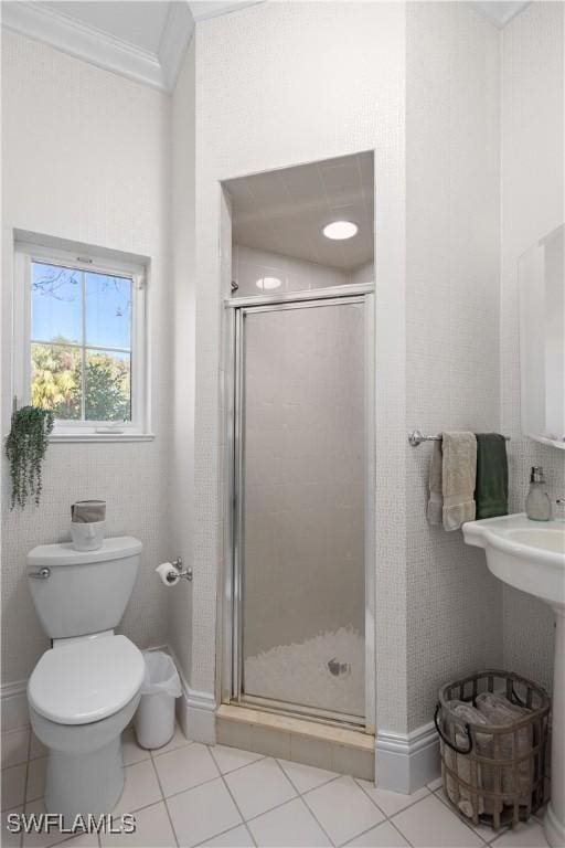 bathroom featuring tile patterned floors, crown molding, toilet, and a shower with door