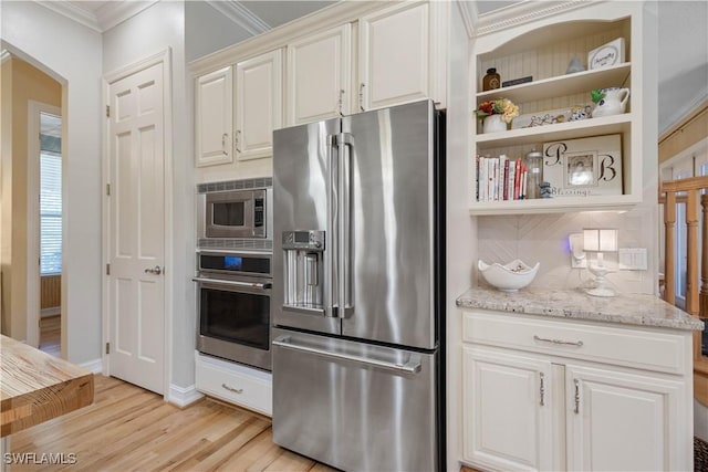 kitchen with appliances with stainless steel finishes, light stone counters, white cabinetry, light hardwood / wood-style floors, and ornamental molding