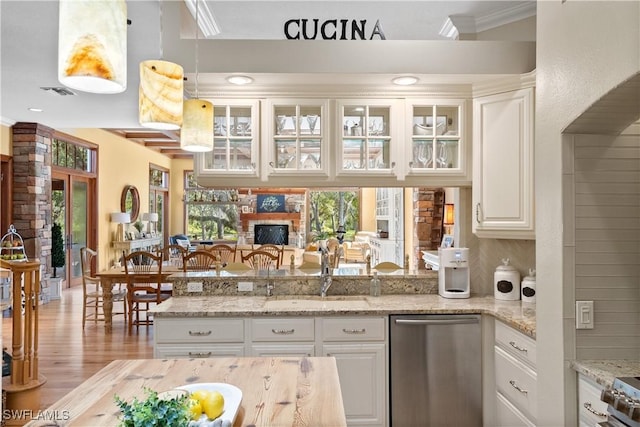 kitchen featuring sink, light stone counters, white cabinetry, dishwasher, and decorative light fixtures