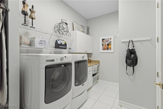 washroom with washing machine and dryer, light tile patterned floors, and cabinets