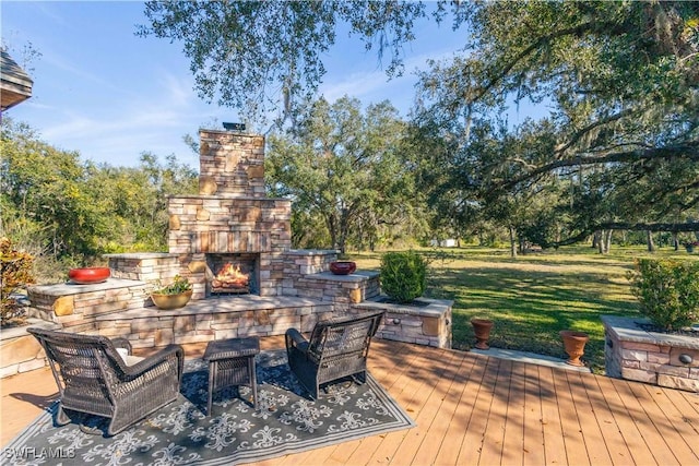 wooden deck with an outdoor stone fireplace and a lawn