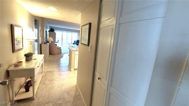 hallway with light tile patterned floors and a textured ceiling