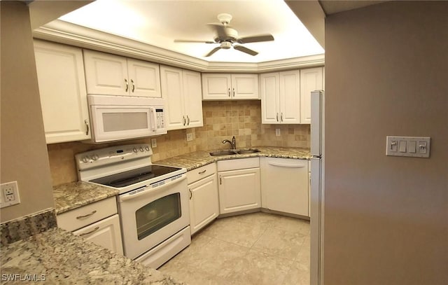 kitchen featuring sink, white appliances, white cabinetry, backsplash, and light stone countertops