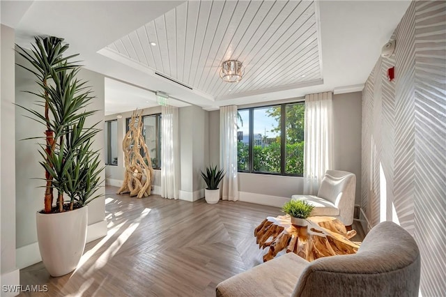 sitting room featuring a raised ceiling, parquet flooring, crown molding, and wood ceiling