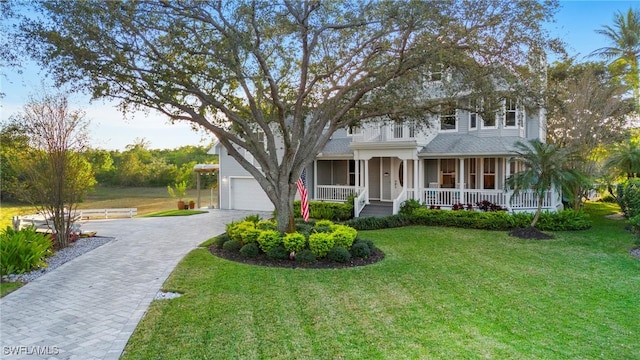 view of front of property featuring decorative driveway, a front yard, and covered porch