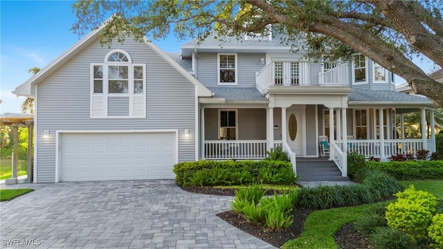 view of front of home with decorative driveway, covered porch, a garage, a shingled roof, and a balcony