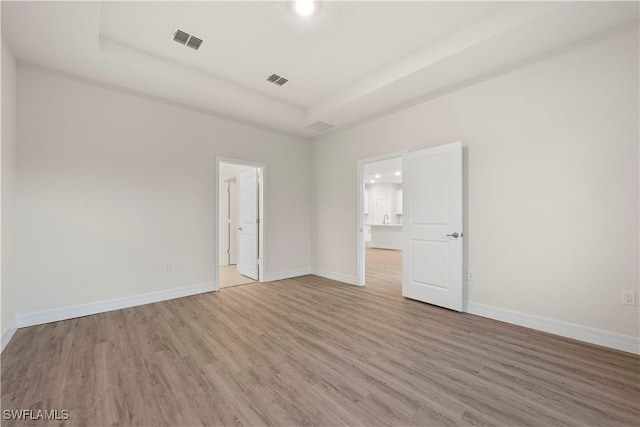 unfurnished room with a tray ceiling and wood-type flooring