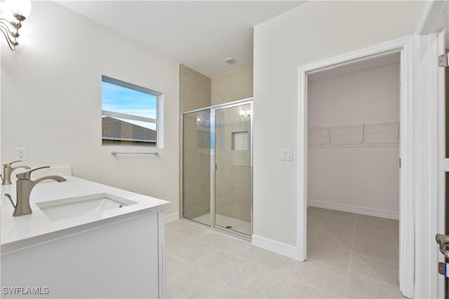 bathroom with a textured ceiling, vanity, tile patterned flooring, and an enclosed shower