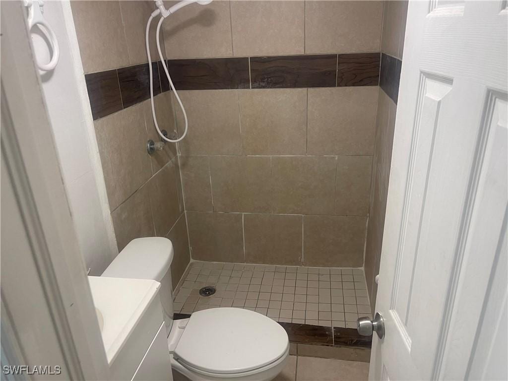 bathroom with vanity, a tile shower, and toilet