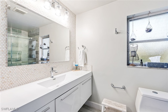 bathroom with vanity, an enclosed shower, toilet, and tasteful backsplash