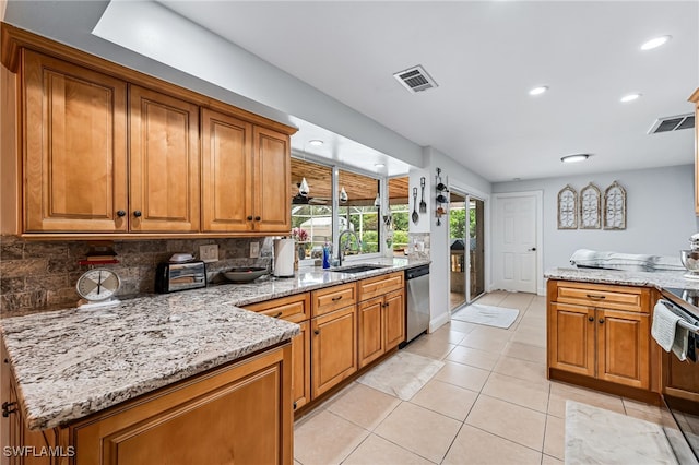 kitchen with stainless steel appliances, light stone countertops, sink, backsplash, and light tile patterned flooring