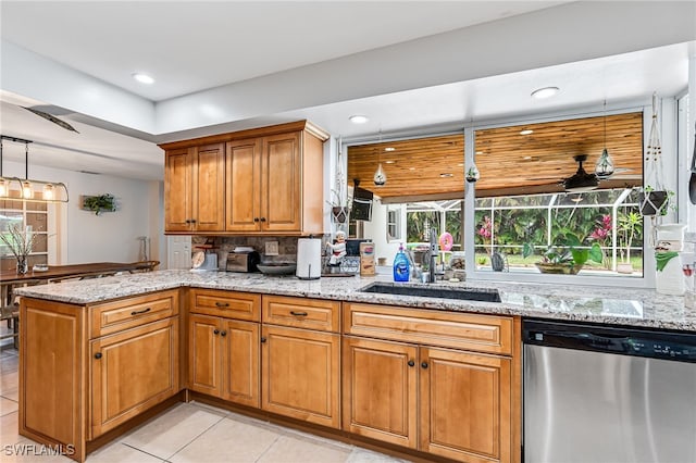 kitchen featuring sink, kitchen peninsula, stainless steel dishwasher, and light stone counters