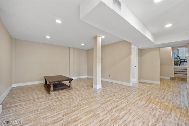 finished basement with recessed lighting, visible vents, light wood-type flooring, baseboards, and stairs