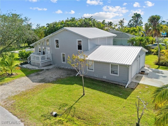 rear view of property featuring a yard, metal roof, and driveway