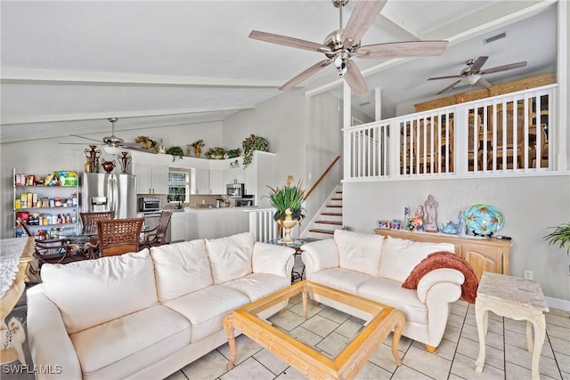 living area with lofted ceiling with beams, light tile patterned floors, stairway, and a ceiling fan