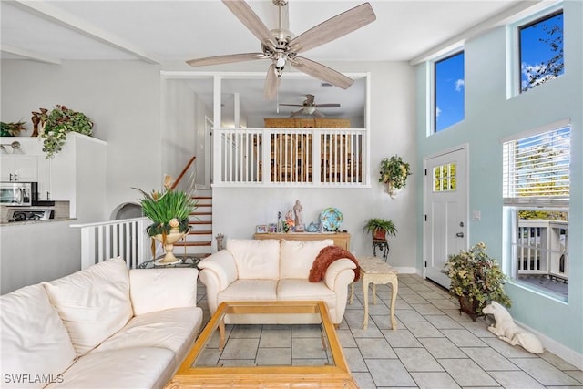 living room featuring a towering ceiling, light tile patterned floors, baseboards, and stairway