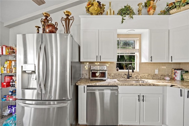 kitchen with light stone counters, a sink, white cabinetry, appliances with stainless steel finishes, and tasteful backsplash