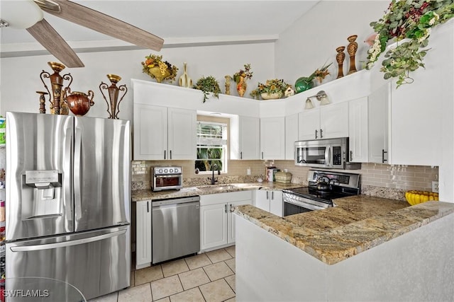 kitchen featuring light stone counters, a sink, white cabinets, appliances with stainless steel finishes, and decorative backsplash