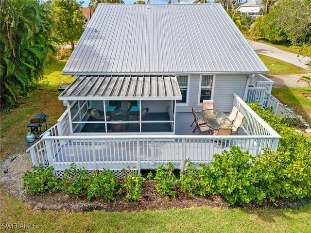 rear view of house featuring a wooden deck, metal roof, and outdoor dining space